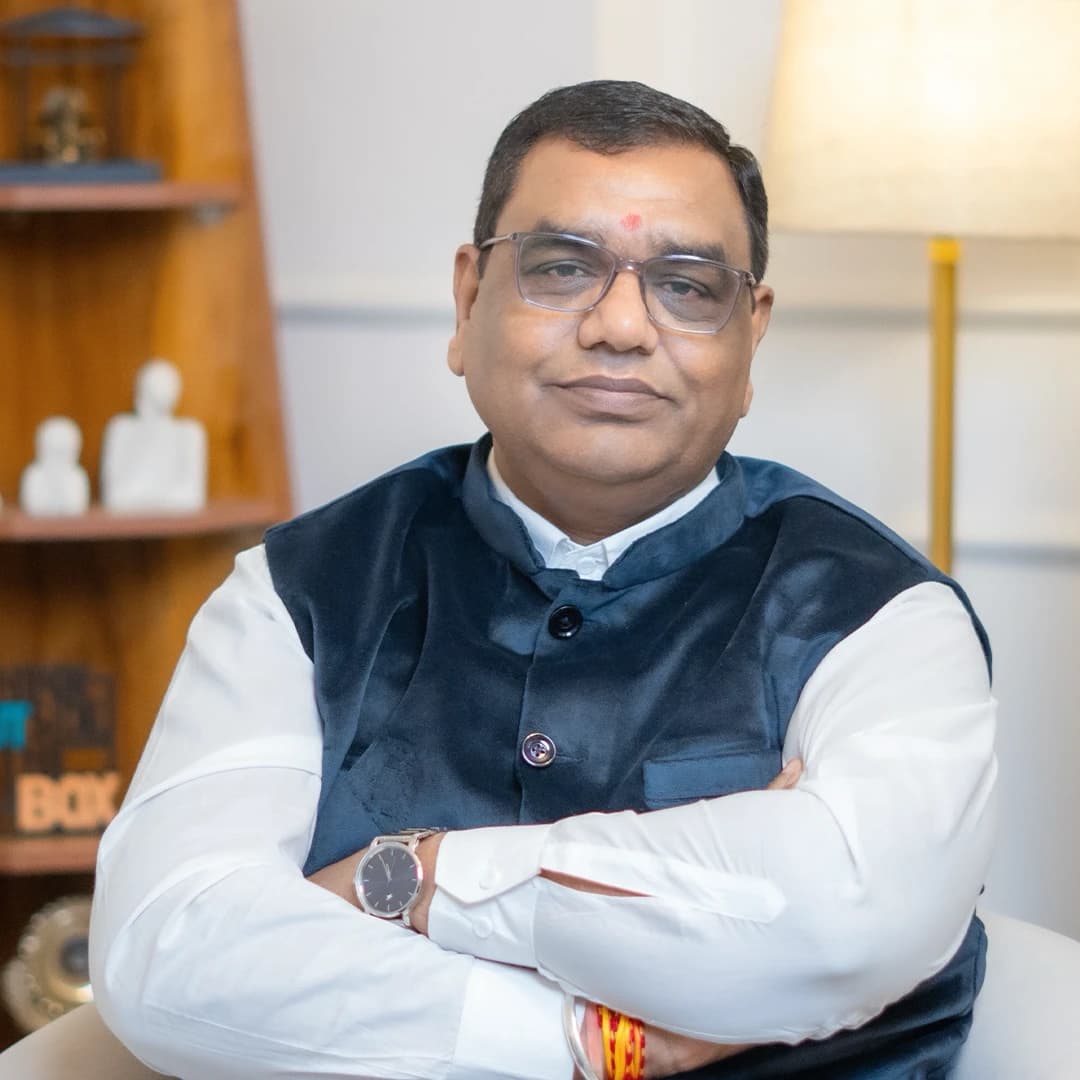 Acharya Chetan Joshi, seated with arms folded, in a navy waistcoat